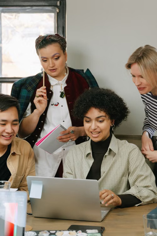 Diverse coworkers planning technology strategy together around a laptop.