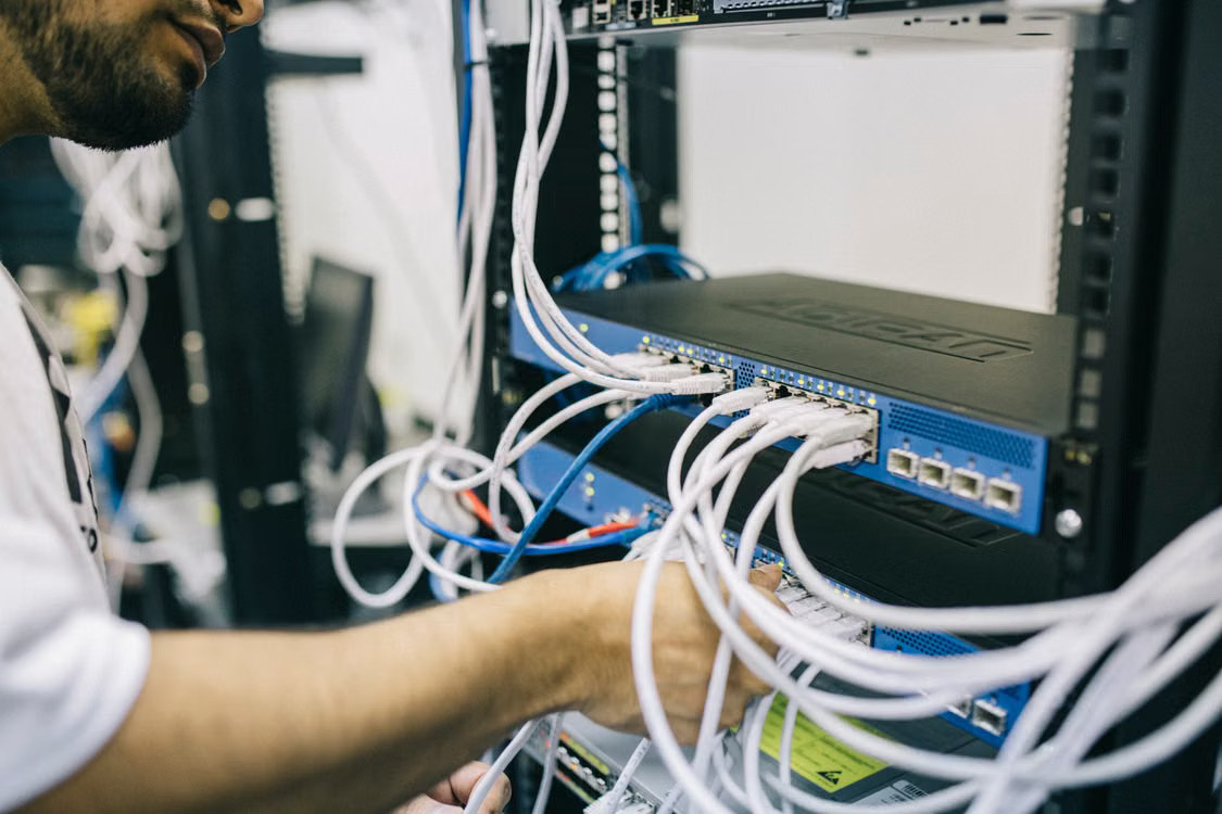 Technician checking cables inside a server cabinet.